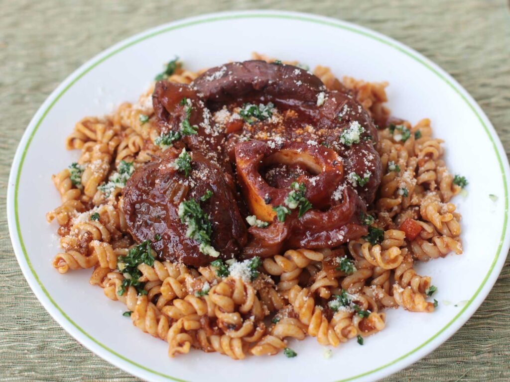 Osso buco with gremolata served over pasta
